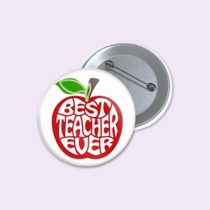 May include: A white button with a red apple design. The apple contains the words "BEST TEACHER EVER" in a stylized font. A second button is visible, showing the pin back.