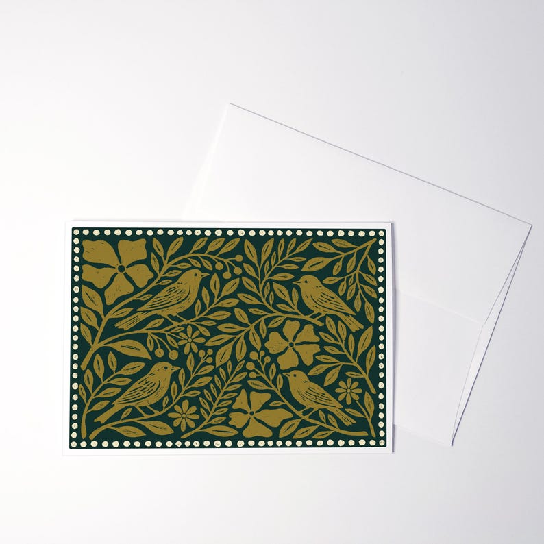 Puede incluir: Una tarjeta de felicitaci&oacute;n rectangular con un fondo verde oscuro y un patr&oacute;n dorado repetitivo de cuatro p&aacute;jaros posados entre flores, hojas y bayas estilizadas, todo ello encerrado en un borde de peque&ntilde;os puntos blancos y un sobre blanco.