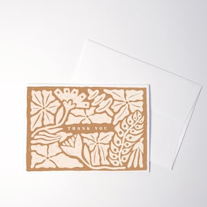 K&ouml;nnte beinhalten: Eine rechteckige Gru&szlig;karte mit terrakottafarbenem Hintergrund und cremefarbenen Blumenillustrationen. In der Mitte der Karte befindet sich der Text THANK YOU in einer einfachen Serifenschrift, umgeben von verschiedenen stilisierten Pflanzenmotiven.