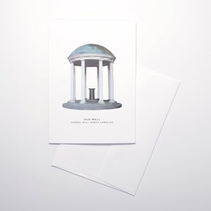 May include: A white greeting card featuring an illustration of the Old Well in Chapel Hill, North Carolina. The artwork depicts the iconic structure with a domed roof and columns. A white envelope is next to the card.