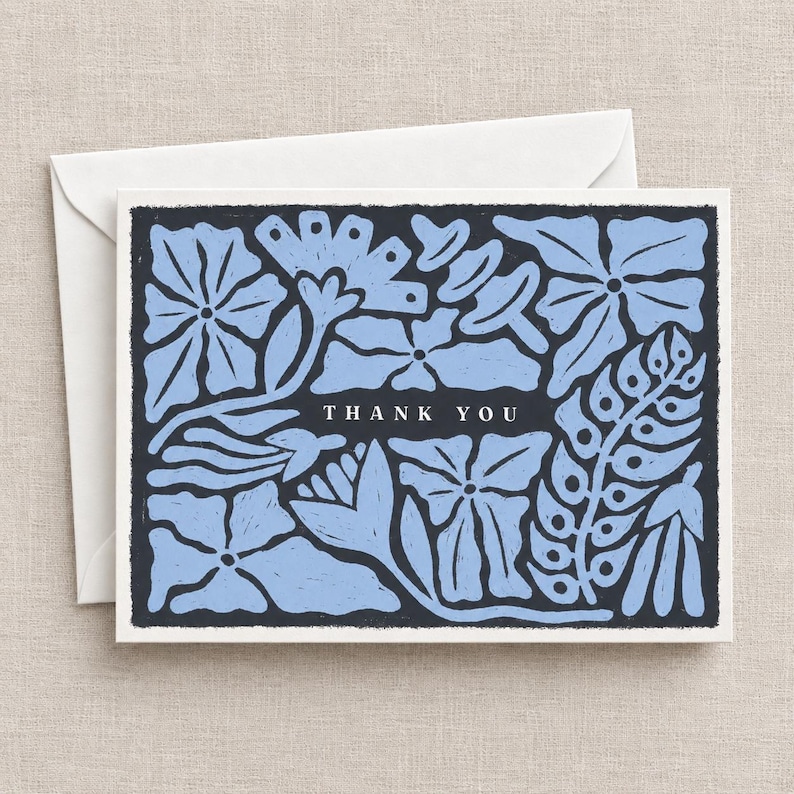 K&ouml;nnte beinhalten: Eine rechteckige Gru&szlig;karte mit dunkelgrauem Hintergrund und hellblauen Blumenillustrationen. Der Text THANK YOU ist in Wei&szlig; in der Mitte aufgedruckt. Die Karte wird mit einem schlichten wei&szlig;en Umschlag geliefert, was ein klares Set ergibt.