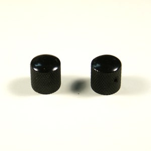 May include: Two black metal guitar knobs with a knurled texture.