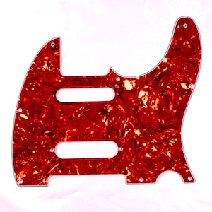 Peut inclure: Un pickguard de guitare électrique en écaille de tortue rouge et blanche. Le pickguard a trois découpes pour les micros et une seule découpe pour un bouton de commande.