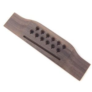 May include: A dark brown wooden guitar bridge with 14 holes for string placement.