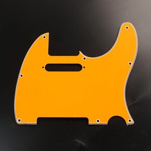 May include: An orange guitar pickguard with a white trim. The pickguard has a unique shape with several screw holes and a long, horizontal pickup slot. The pickguard is designed for a specific guitar model.