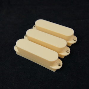 May include: Three cream-colored guitar pickup covers with gold screws.