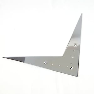 May include: A silver metal guitar pickguard with a pointed shape and multiple screw holes.