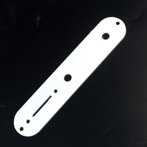 May include: A white, rectangular guitar part with rounded edges. It features several holes of varying sizes and a long, narrow slot. The part is designed for mounting on a guitar body.