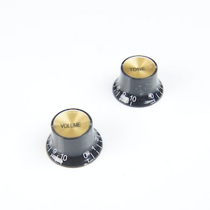 May include: Two black guitar knobs with gold lettering. The knob on the left says "VOLUME" and the knob on the right says "TONE". Both knobs have white numbers from 0 to 10.