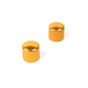 May include: Two gold-coloured metal knobs with a textured surface. The knobs are round and have a cylindrical shape.