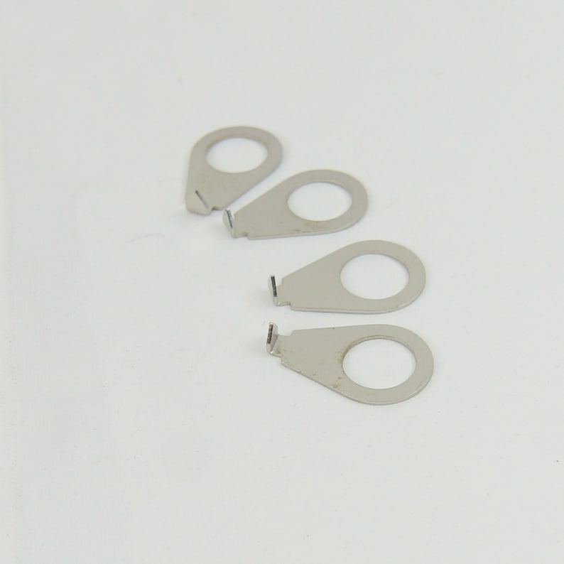 May include: Four silver metal guitar strap buttons with a small hole in the centre of each button.