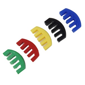 May include: Five violin mute adjusters in different colours: blue, black, yellow, red, and green. Each mute is a curved plastic piece with five teeth.