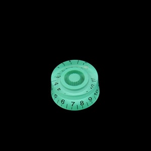 May include: A green plastic knob with black numbers 1 through 10 and a small centre hole.