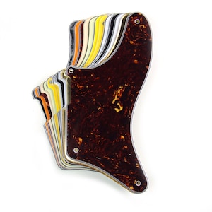 Puede incluir: Una pila de placas de protección de guitarra en varios colores, incluyendo negro, blanco, amarillo, naranja y marrón. Las placas de protección están hechas de un material similar a la carey y tienen una forma de guitarra clásica.
