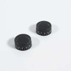 May include: Two black round knobs with white numbers. The knob on the left has numbers 1 through 6. The knob on the right has numbers 5 through 10.