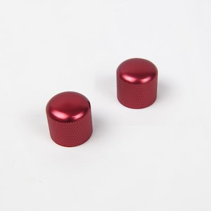 Puede incluir: Dos pomos de metal rojo con una superficie texturizada.