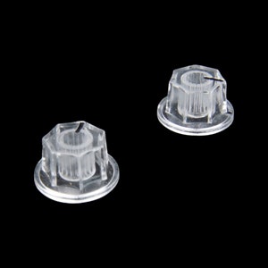 May include: Two clear plastic knobs with a hexagonal shape and a raised center. The knobs have a smooth, glossy finish.