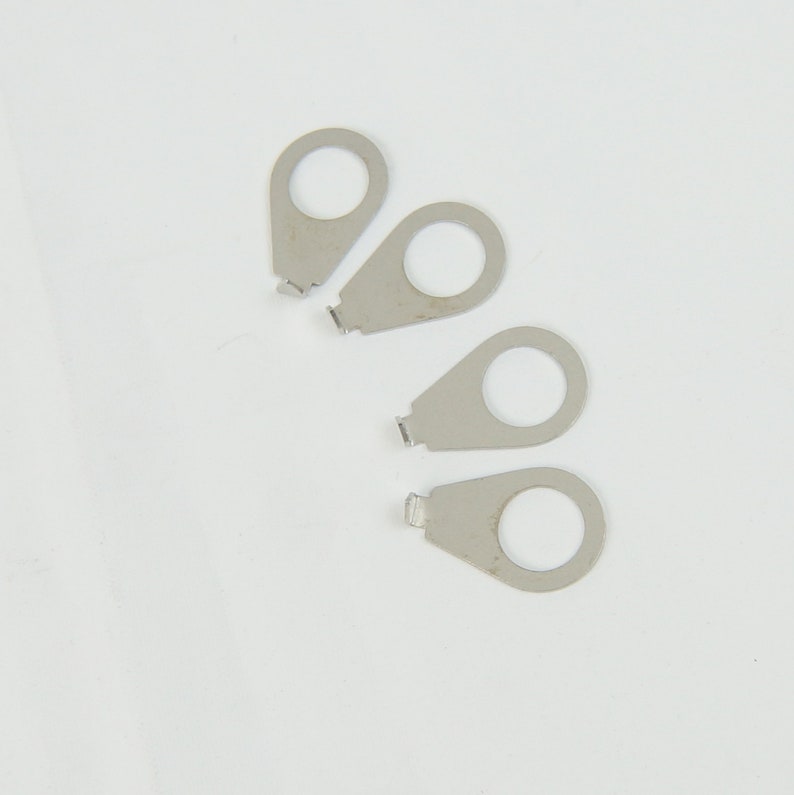 May include: Four silver guitar string tuning pegs. The pegs are shaped like a teardrop with a small hole in the centre.