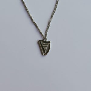 May include: A silver chain necklace with a silver harp pendant. The harp is a traditional Irish symbol.