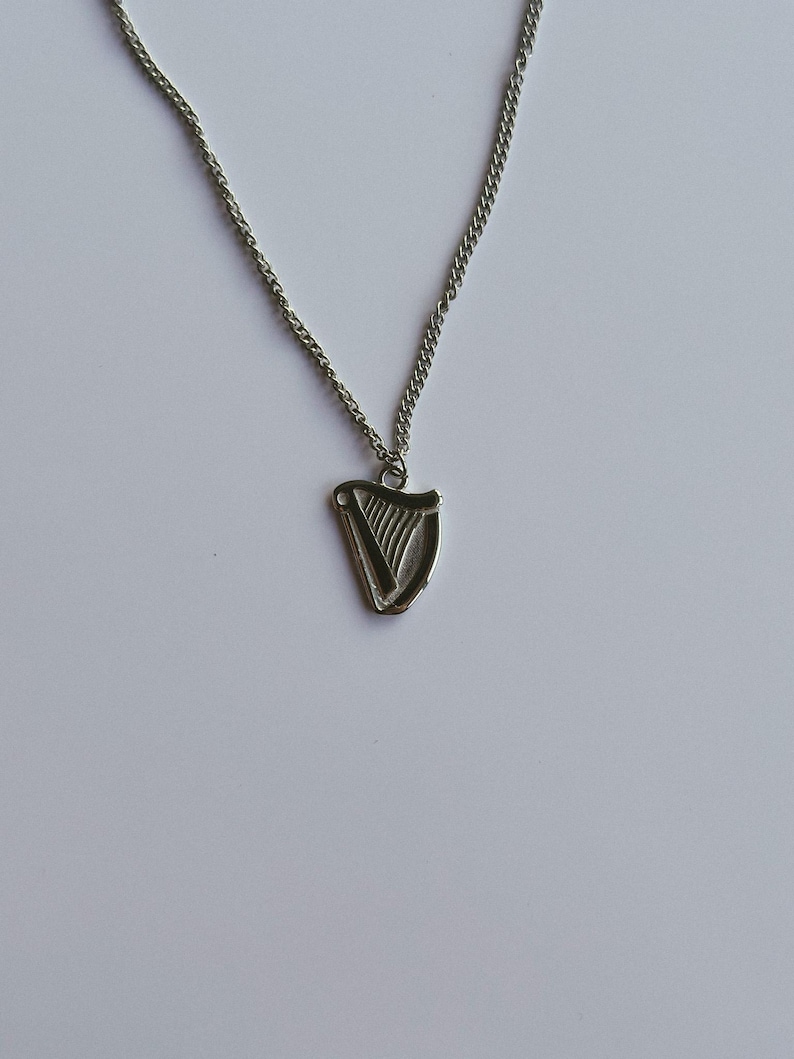 May include: A silver chain necklace with a silver harp pendant. The harp is a traditional Irish symbol.