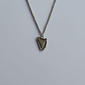 May include: A silver chain necklace with a silver harp pendant.