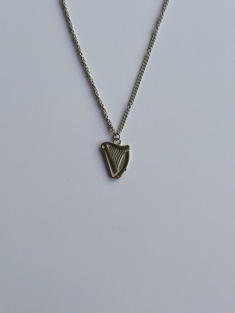 May include: A silver chain necklace with a silver harp pendant.