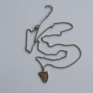May include: A silver chain necklace with a silver harp pendant.
