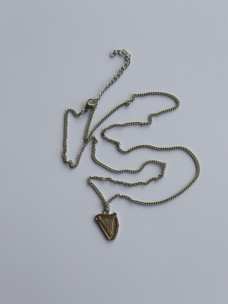 May include: A silver chain necklace with a silver harp pendant.