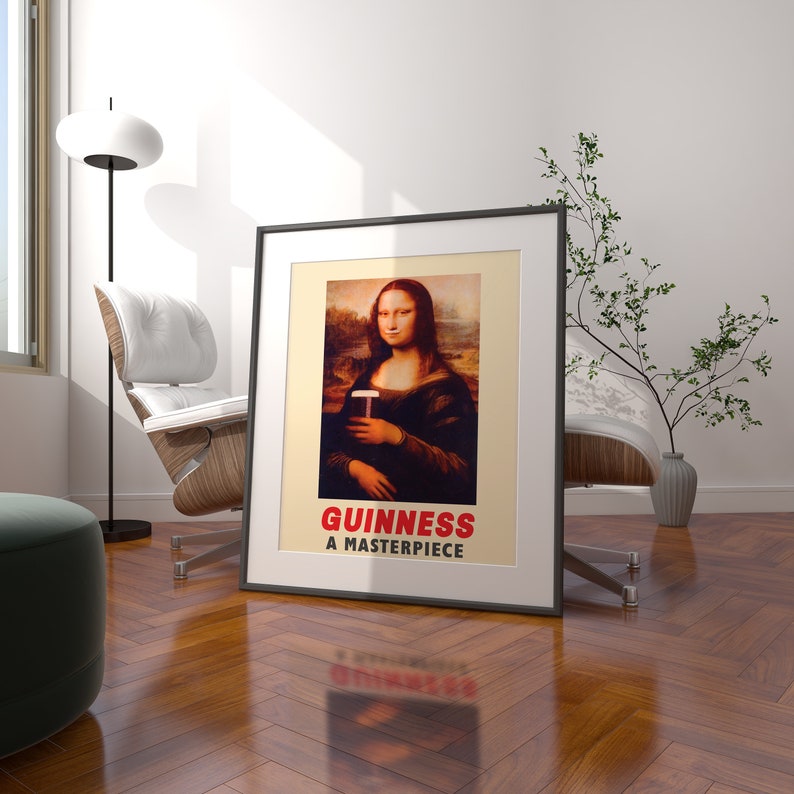 May include: A framed poster with a black frame and a white background. The poster features a painting of the Mona Lisa holding a glass of Guinness beer. The text below the painting reads "GUINNESS A MASTERPIECE."