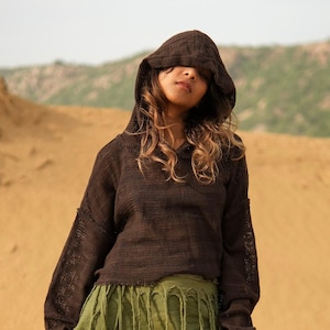 May include: A dark brown, long-sleeved, hooded pullover jumper made of a lightweight, semi-sheer, open-knit fabric. The garment features a relaxed fit with dropped shoulders, a raw-edge hemline, and a hood that covers the upper portion of the head.
