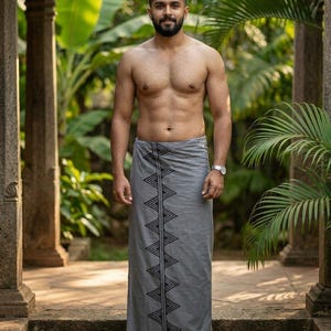 Puede incluir: Un sarong gris con un patrón geométrico negro. El sarong lo lleva una persona de pie sobre escalones de piedra. El fondo incluye un exuberante follaje verde y columnas de piedra. La persona lleva un reloj de pulsera y sandalias.