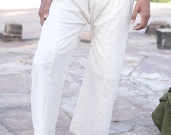 May include: Off-white, wide-leg trousers featuring a wrap-around waist design with a folded top band. The pants are crafted from a textured, light-colored fabric and fall to a straight-cut hem, providing a loose and relaxed fit.