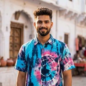 May include: A short-sleeved shirt with a vibrant tie-dye pattern in shades of blue, pink, and white. The shirt has a button-down front and a chest pocket. The shirt is made of a soft, comfortable material.