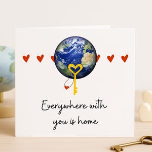 En cualquier lugar contigo está el hogar: tarjeta romántica de aniversario con el planeta Tierra y una llave, amor a distancia o celebración entre marido y mujer.