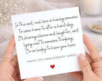 Könnte beinhalten: Eine quadratische weiße Grußkarte mit schwarzem kursivem Text: In the end, real love is having someone to come home to after a hard day. It's sharing silence and laughter, and lying next to someone thinking, I'm so lucky to have you here. HAPPY 9TH ANNIVERSARY JAMES mit einem kleinen roten Herzsymbol unter dem Text.