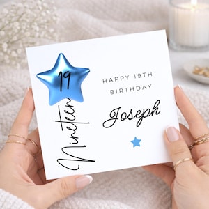 May include: A square white greeting card featuring a metallic blue star with the number 19, the text "HAPPY 19TH BIRTHDAY", the name "Joseph" in script, the word "Nineteen" written vertically, and a small solid blue star icon.