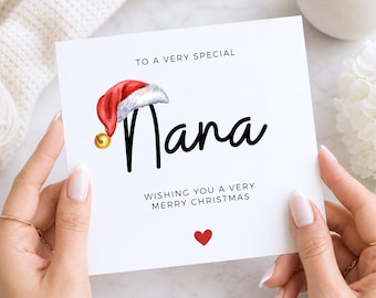 May include: A square white greeting card featuring the text TO A VERY SPECIAL Nana WISHING YOU A VERY MERRY CHRISTMAS in black font. A red and white Santa hat with a small gold bell sits atop the letter N, and a small red heart is below.
