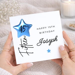 Peut inclure: Carte de joyeux anniversaire blanche avec une étoile bleue et le texte "Happy 15th Birthday Joseph". Le mot "Fifteen" est écrit verticalement en cursive. Une petite étoile bleue est également présente.