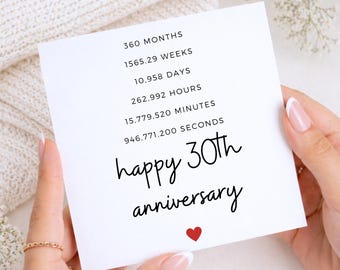 May include: A square white greeting card featuring black text that lists 360 months, 1565.29 weeks, 10,958 days, 262,992 hours, 15,779,520 minutes, and 946,771,200 seconds, followed by the phrase happy 30th anniversary and a small red heart.