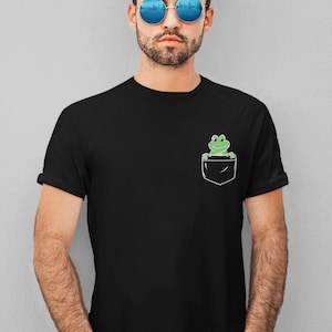 May include: A black t-shirt with a green frog peeking out of the pocket.