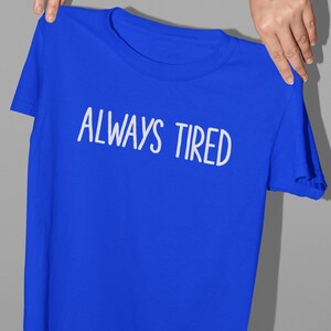K&ouml;nnte beinhalten: Ein k&ouml;nigsblaues T-Shirt mit dem Aufdruck "ALWAYS TIRED" in Wei&szlig;.
