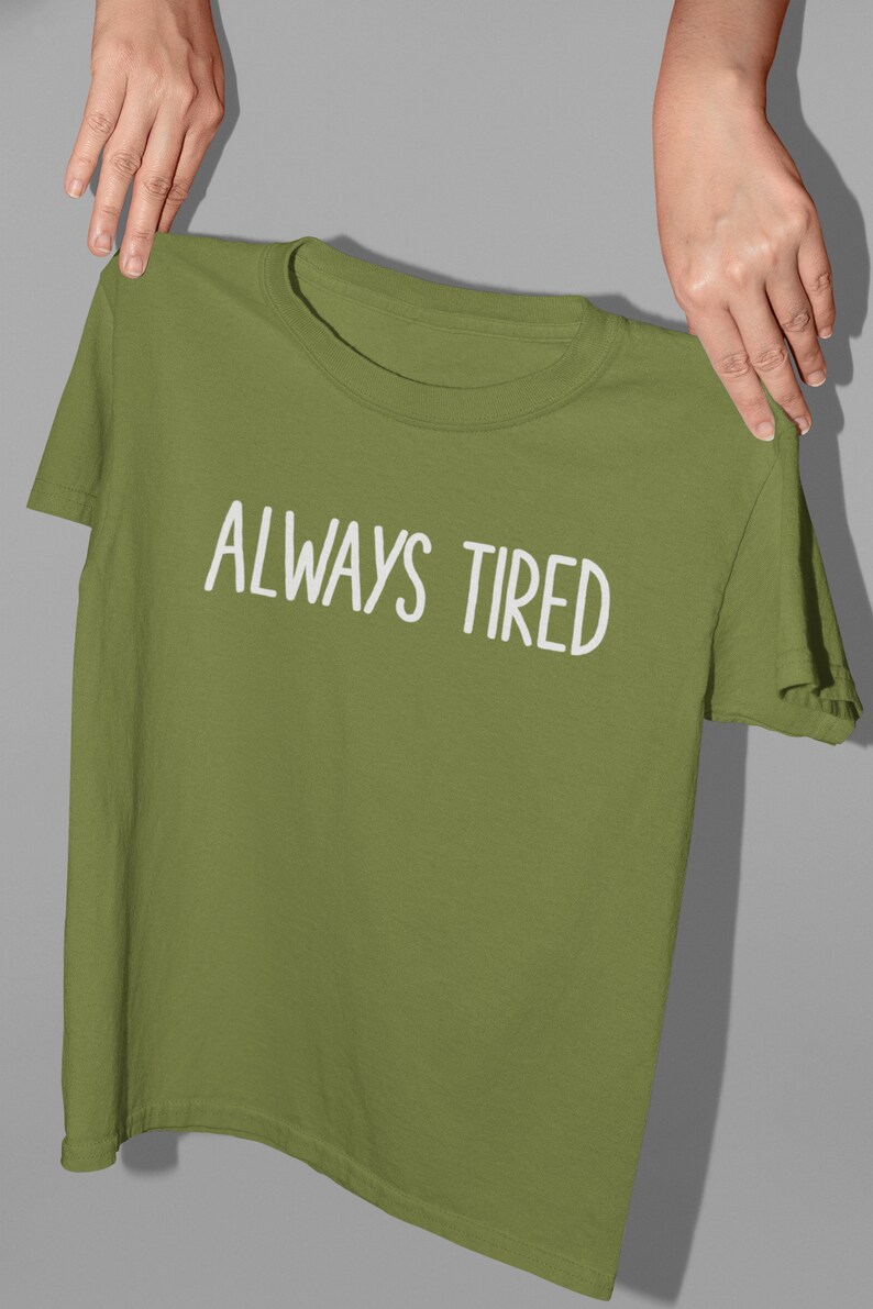 K&ouml;nnte beinhalten: Ein gr&uuml;nes T-Shirt mit dem Text "ALWAYS TIRED" in wei&szlig;en Buchstaben.