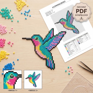 May include: A hummingbird pattern made of colourful plastic fuse beads, accompanied by a printed PDF instruction sheet titled HUMMINGBIRD. The sheet includes a grid, bead counts, and colour keys. Loose beads in yellow, teal, and pink are scattered nearby.