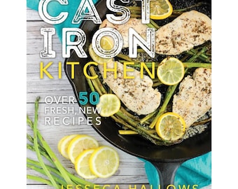 May include: A cookbook cover with a cast iron skillet filled with chicken, asparagus, and lemon slices. The title of the book is "Cast Iron Kitchen" and the subtitle is "Over 50 Fresh, New Recipes". The author is Jesseca Hallows.