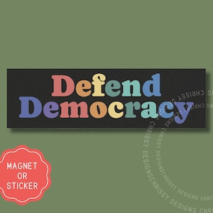 Pode incluir: Um ímã ou adesivo retangular preto com o texto "Defend Democracy" em cores do arco-íris.