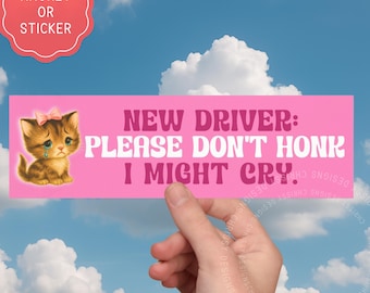 May include: A pink magnet or sticker with the text "NEW DRIVER: PLEASE DON'T HONK I MIGHT CRY." features a crying kitten with a pink bow. The background is a blue sky with white clouds.