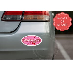 May include: Pink oval magnet or sticker with the text "Abolish ICE" in a retro font. The design includes cherries and stars. The magnet is attached to the back of a silver car.