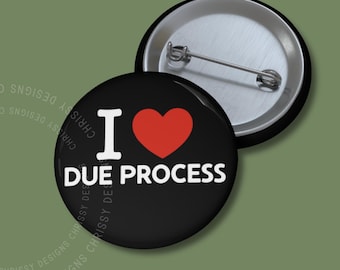 Pode incluir: Um botão preto com um design branco "Eu amo o devido processo legal". O coração é vermelho.