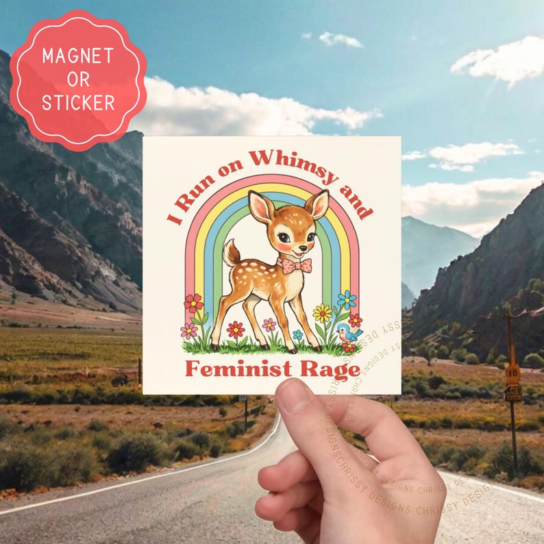 May include: Square magnet or sticker featuring a cartoon fawn with a pink bow tie, standing in front of a rainbow. Text reads "I Run on Whimsy and Feminist Rage". The background shows a mountain landscape.