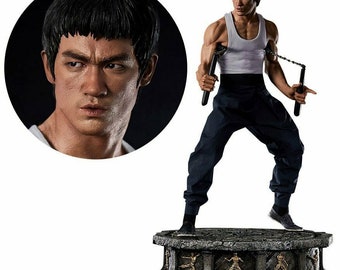 May include: A collectible statue of a martial arts figure in a white tank top and black pants holding two nunchucks. The statue is posed in a fighting stance and is standing on a stone base with decorative carvings.